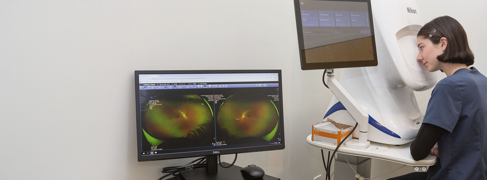 The image shows a person sitting at a computer with medical equipment behind them, possibly monitoring or analyzing medical images on a screen.