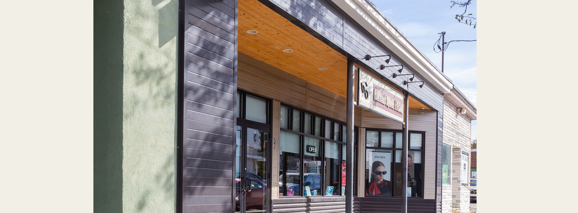 The image shows a building with a modern architectural design, featuring a facade with large glass windows and a combination of dark and light-colored materials, possibly wood and stone, with a visible entranceway and a sign that appears to be partially obscured.